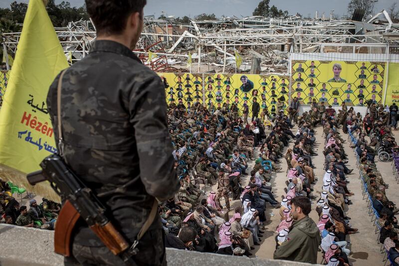 A Syrian Democratic Forces fighter watches over guests attending the victory ceremony announcing the defeat of ISIS  in Deir Al Zor, Syria. Getty