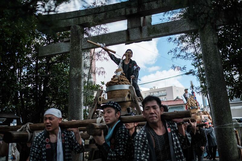 A large fireworks cylinder is carried by a group of men before dedicating the fireworks to the Yoshida Shrine. AFP