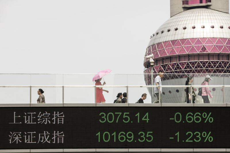 People walk along an elevated walkway as an electronic ticker displays the figures of the Shanghai Composite Index, top, and the SZSE Composite Index in Pudong's Lujiazui Financial District in Shanghai, China, on Saturday, June 2, 2018. China's banks, scrambling to adjust to the government's deleveraging campaign, are likely to add to pressures on the corporate bond market as they shed more of their massive note holdings and de-risk their balance sheets. Photographer: Qilai Shen/Bloomberg