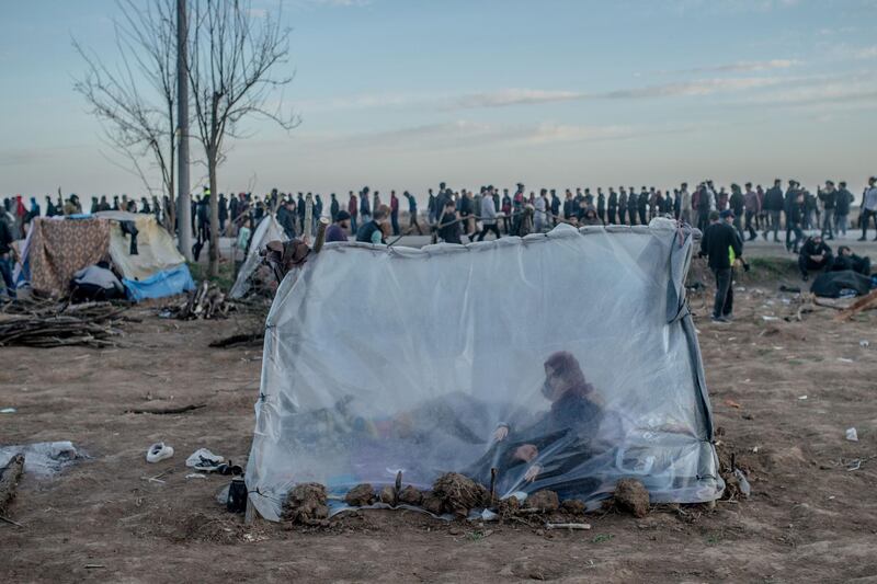 A Syrian woman sits in a tent with her son as others wait for food distribution in front of the Pazarkule border crossing to Greece, in Edirne.  AFP