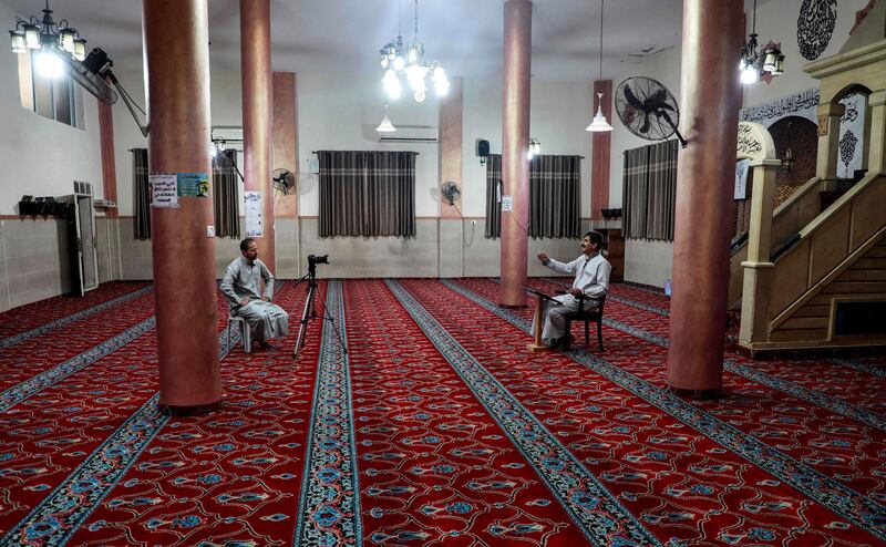 A Palestinian preacher speaks before a camera while recording a sermon and broadcasting the audio onto loudspeakers inside an empty mosque in the village of Salem east of Nablus in the occupied West Bank on the first day of Ramadan on April 24, 2020. AFP