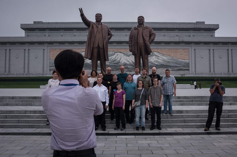 Tourists pose for a group photo before statues of late North Korean leaders Kim Il-Sung and Kim Jong-Il, on Mansu hill in Pyongyang. AFP