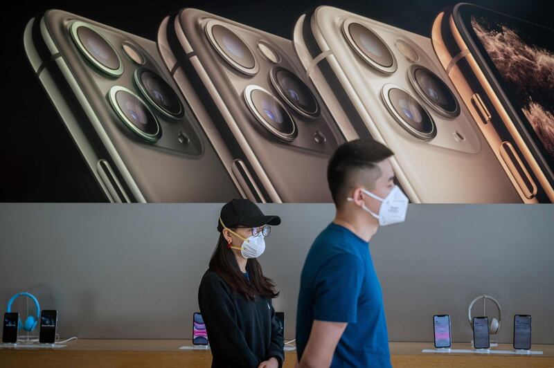 In this picture taken on March 11, 2020 Apple staff wearing face masks as a preventive measure against the COVID-19 coronavirus wait for customers at an Apple shop in Beijing. The number of fresh infections at the epicentre of China's COVID-19 coronavirus epidemic dropped to a new low on March 12 but the country imported more case from abroad. / AFP / NICOLAS ASFOURI
