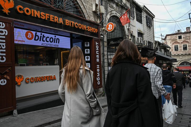 People pass by a cryptocurrency exchange branch near the Grand Bazaar in Istanbul. Mainstream companies are increasingly accepting cryptocurrencies as payments. AFP