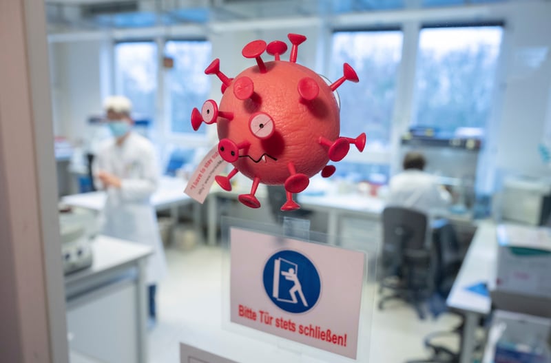 A rubber figure in the shape of a virus hangs on the door of the PCR laboratory in the Lower Saxony State Health Office in Hanover, Germany. AP
