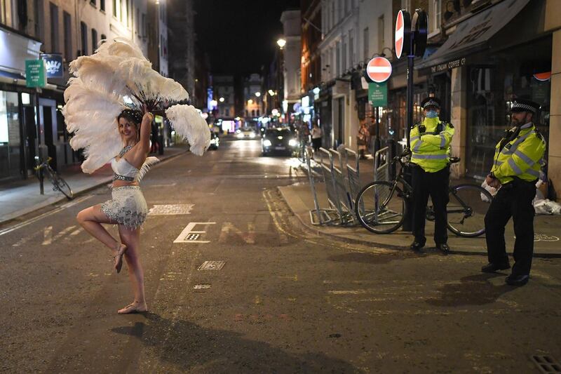 Police officers look on as an entertainer walks past in Soho in London, England. Getty Images