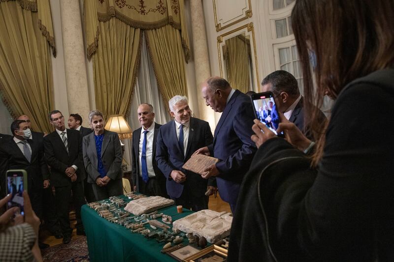 Mr Lapid presents Mr Shoukry with stolen Egyptian artefacts that were smuggled to Israel, at Tahrir Palace in Cairo.  AP