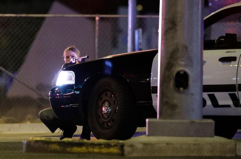 A police officer takes cover behind a police vehicle during a shooting near the Mandalay Bay resort and casino on the Las Vegas Strip. John Locher / AP Photo