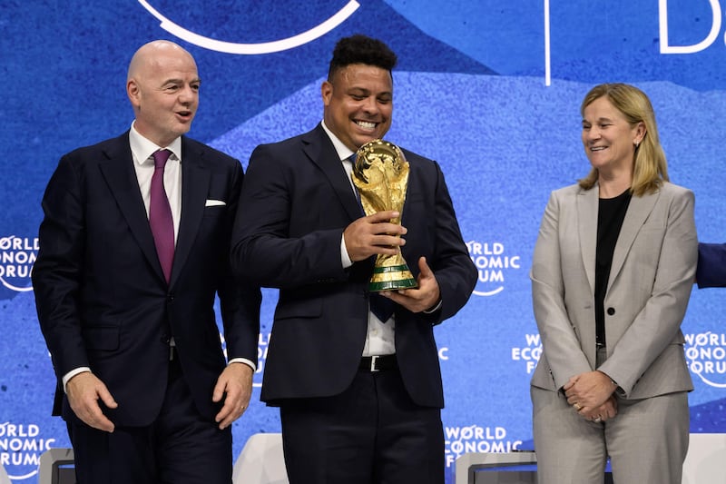 (L-R) Fifa president Gianni Infantino, former Brazilian footballer Ronaldo with the World Cup trophy and former footballer and coach Jill Ellis in Davos. AFP