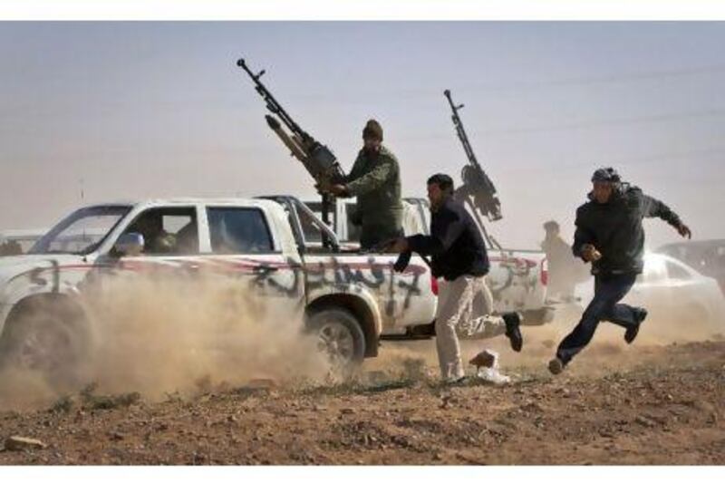 Rebel fighters shoot the tyres out of a vehicle, unseen, belonging to Col Qaddafi's forces as it sped through the rebel front line, east of Brega, yesterday. The vehicle was driven by a young boy who said he had spent two days in besieged Brega and stole the vehicle in order to return to the rebel side.