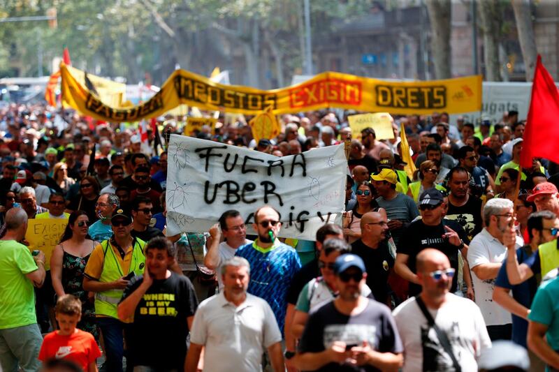 Taxi drivers hold a sign reading "Uber out" as they march during a strike by cab drivers in Barcelona.  AFP / Pau Barrena
