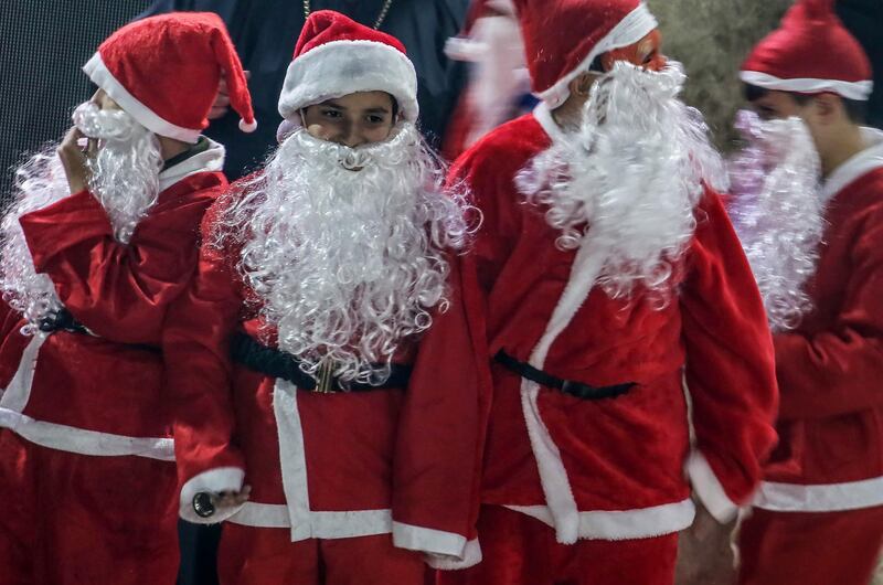 epa08042302 Palestinian boys in Santa costumes attend a ceremony of lighting a Christmas tree in Gaza City, 03 December 2019. The event was organised by the YMCA Gaza.  EPA/MOHAMMED SABER