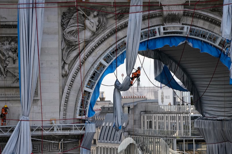 A technician is suspended in the arch way of the monument, as the final artwork of Christo and Jean Claude is taken apart.  AP Photo 