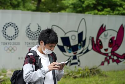 epa08437044 A young man wearing a face mask walks past Tokyo Olympics logos in Tokyo, Japan, 22 May 2020. Three new coronavirus infections were reported in the Japanese capital, the lowest figure since the state of emergency was declared in April.  EPA/FRANCK ROBICHON