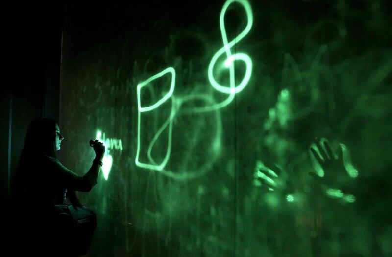 A visitor uses a UV light to paint on the installation ‘Glowing Wall’ by Greek artist Vassilis Kambouris at the 13th Digital Arts Festival in Athens. Simela Pantzartzi / EPA