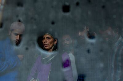 Kashmiri villagers are seen through the bullet ridden iron mesh of a window of a home where suspected rebels were taking refuge, after a gunfight in Pulwama, south of Srinagar, last month. AP Photo