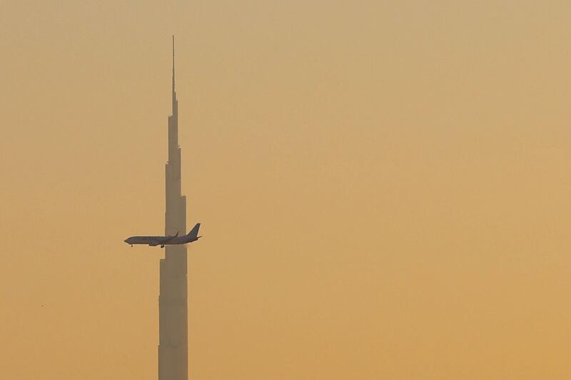 A commercial airplane flies past Burj Khalifa as it starts landing at Dubai international airport in the United Arab Emirates, on January 9, 2021. / AFP / GIUSEPPE CACACE
