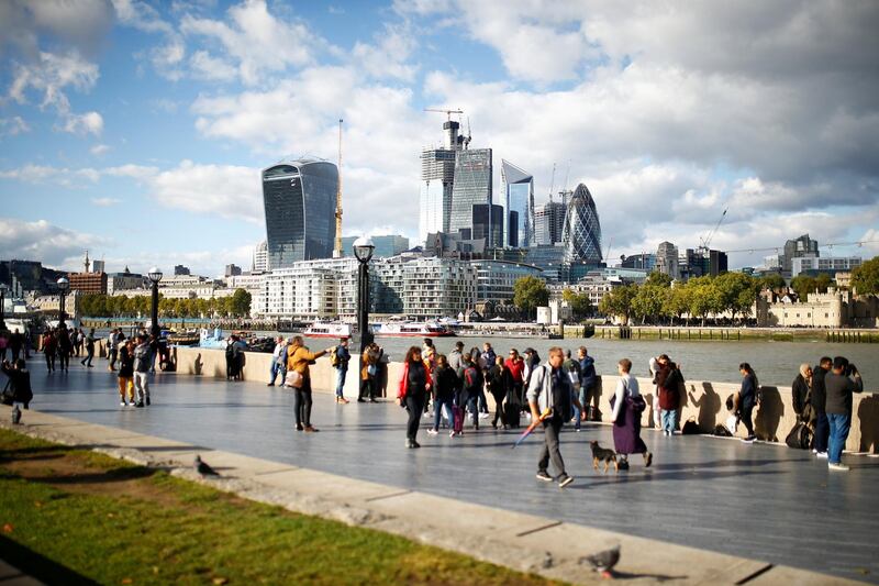 People walk by the River Thames across from the financial district of London in the UK. Henry Nicholls/Reuters