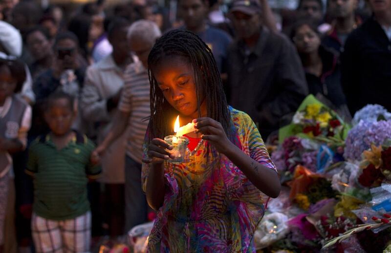 A girl lights a candle for South African former president Nelson Mandela at a wall of flowers laid by mourners outside Mandela’s home in Houghton, Johannesburg. Pedro Ugarte / AFP Photo