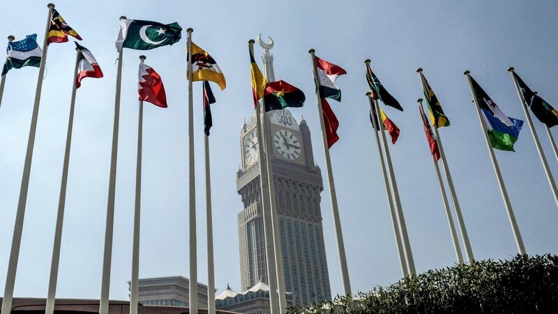 A picture taken on November 17, 2016 shows the national flags of the members of Organisation of Islamic Cooperation (OIC) states flying in front of the clock of the Abraj al-Bait Towers which overlooks the Grand Mosque in the holy city of Mecca. (Photo by STRINGER / AFP)