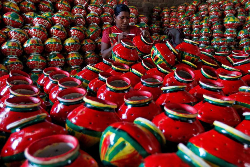 A woman decorates an earthen pitcher typically used during Garba, a folk dance, inside a workshop ahead of Navratri, a festival during which devotees worship the Hindu goddess Durga and youths dance in traditional costumes, in Ahmedabad.  Amit Dave / Reuters