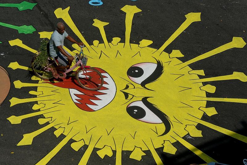 A motorist rides past graffiti painted on a road to raise awareness about coronavirus. AFP