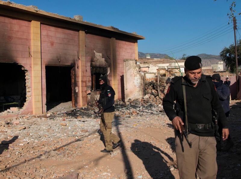 Police officer stand guar in a Hindu temple which was set on fire and demolished by a mob led by Islamists, in Karak, Pakistan, Thursday, Dec. 31, 2020. Pakistani police arrested 24 people in overnight raids after a Hindu temple was set on fire and demolished by a mob led by supporters of a radical Islamist party, officials said. The temple's destruction Wednesday in the northwestern town of Karak also drew condemnation from human rights activists and leaders of Pakistan's minority Hindu community. (AP Photo/Zubair Khan)
