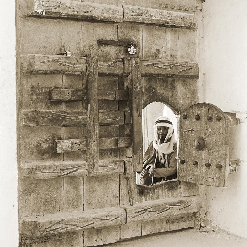 guard looking through an opening in the gate of Al Hosn, 1960.

Courtesy National Center for Documentation and Research.