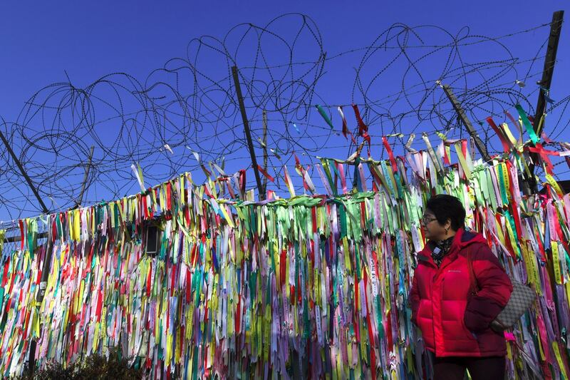 A woman walks past a military fence covered with ribbons calling for peace and reunification at the Imjingak peace park near the Demilitarized Zone (DMZ) dividing the two Koreas in the border city of Paju on January 1, 2018.
Kim Jong-Un vowed North Korea would mass-produce nuclear warheads and missiles in a defiant New Year message on January 1, suggesting he would continue to accelerate a rogue weapons programme that has stoked international tensions. / AFP PHOTO / JUNG Yeon-Je