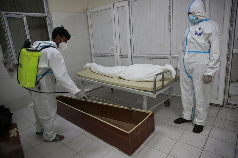 Afghan health workers in protective suits spray disinfectant on the coffin of a person who died from Covid-19.