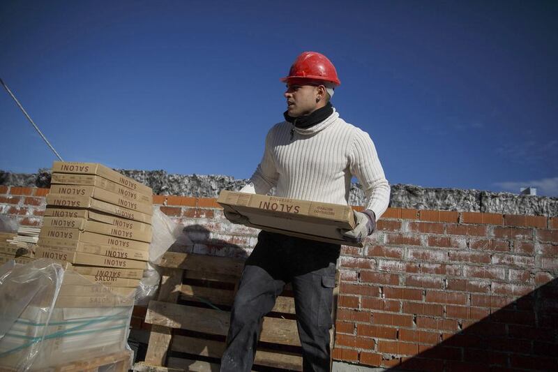 A worker carries tiles at a construction site of a residential block in the Valdebebas neighbourhood. In Madrid, the city council issued 3,131 building permits for residential use in the first 10 months of 2014, more than it awarded in the whole of 2013. Andrea Comas / Reuters