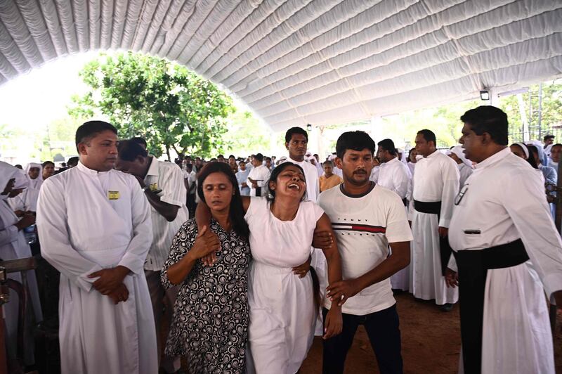 A woman is helped to walk as she cries during funeral. aFP