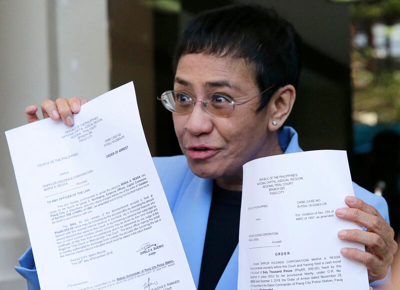 Maria Ressa holds up documents outside a courtroom after posting bail in one of the numerous legal cases brought against her. AP