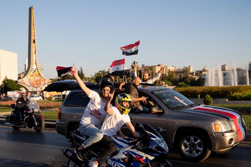 Supporters of Syrian President Bashar Al Assad hold up national flags at an election gathering at Umayyad Square, in the capital Damascus, on Sunday, May 23. AP Photo
