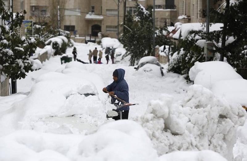 A Palestinian man cleans snow from his car in the West Bank city of Ramallah in December 2013 after a snowstorm. Reuters