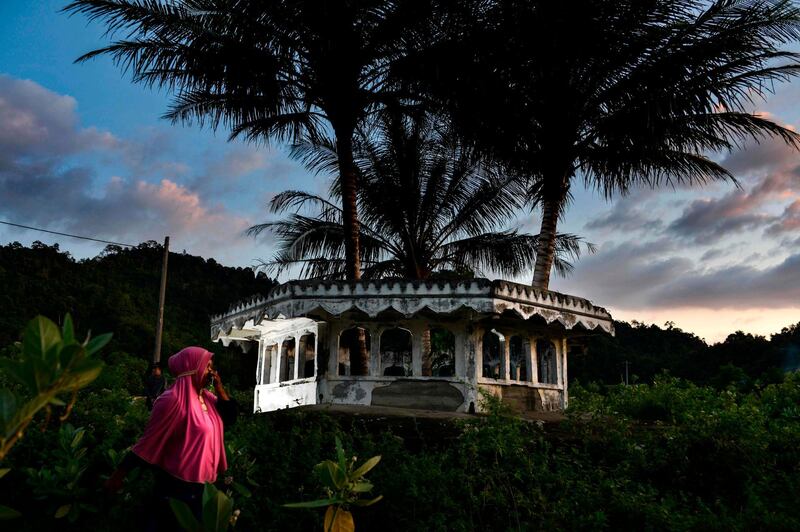 A women walks past a mosque minaret devastated on 2004 by an earthquake and tsunami called 'Boxing Day Tsunami', in Lhokseudu, Aceh province.  AFP