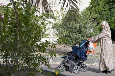 A domestic worker takes a child out for a stroll in the Nad Al Sheba neighbourhood in Dubai. The National