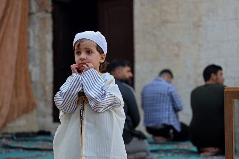 A Syrian child dressed in traditional Damascene dress stands as Muslims attend the prayers of Eid Al Fitr in Syria's rebel-held northwestern city of Idlib. AFP