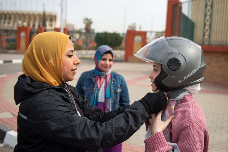 epa09073796 Walaa Zohier founder of Women, Drive Scooters academy helps a trainee put on her helmet during a training session, in Cairo, Egypt, 14 March 2021. The academy is an initiative to teach women to drive scooters for multiple reasons mainly mobility freedom and to seek a sexual harassment free means of transportation.  EPA/Mohamed Hossam