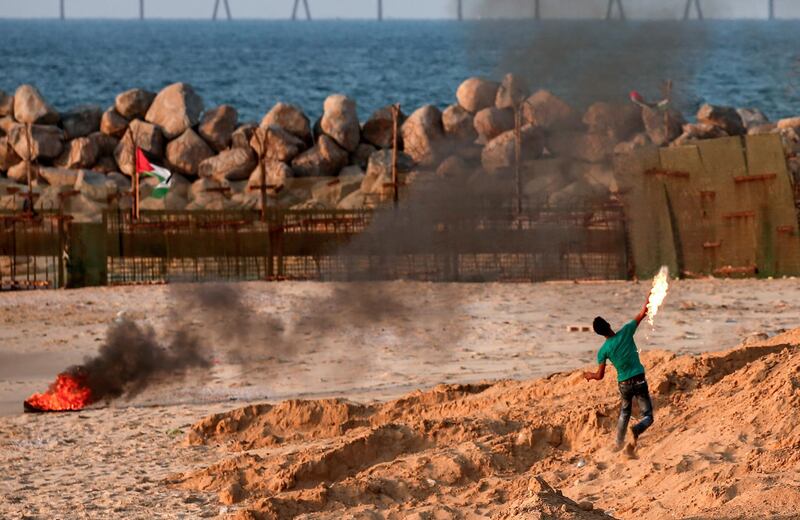 A Palestinian protester throws a molotov cocktail across on a beach along the Gaza sea barrier on the border with Israel near Kibbutz Zikim, north of Beit Lahia in the northern Gaza Strip. AFP
