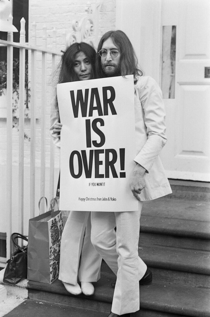 John Lennon (1940 - 1980) and Yoko Ono pose on the steps of the Apple building in London, holding one of the posters that they distributed to the world's major cities as part of a peace campaign protesting against the Vietnam War, December 1969. The poster reads 'War Is Over, If You Want It'. (Photo by Frank Barrett/Keystone/Hulton Archive/Getty Images)
