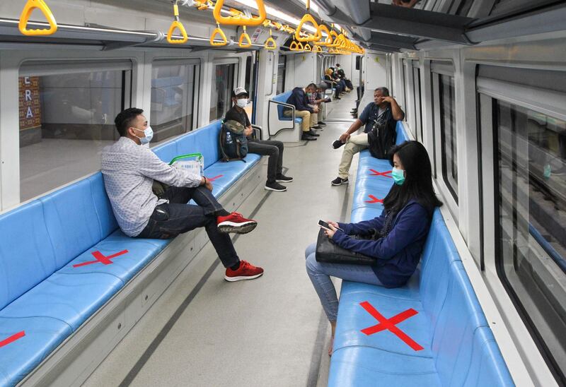 People sit on designated areas decided by red cross marks to ensure social distancing inside a light rapid transit train in Palembang, South Sumatra.  AFP