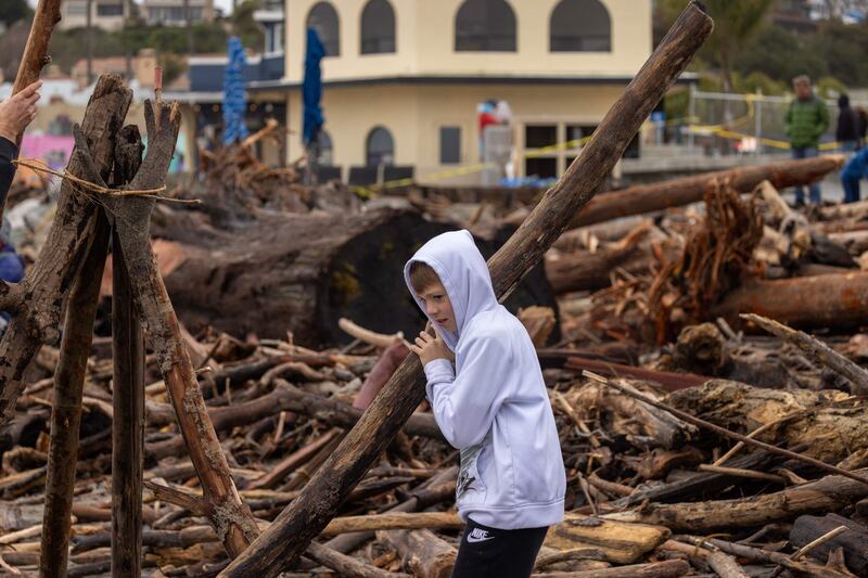 A child holds a tree trunk that was swept into the ocean by recent storms. AFP