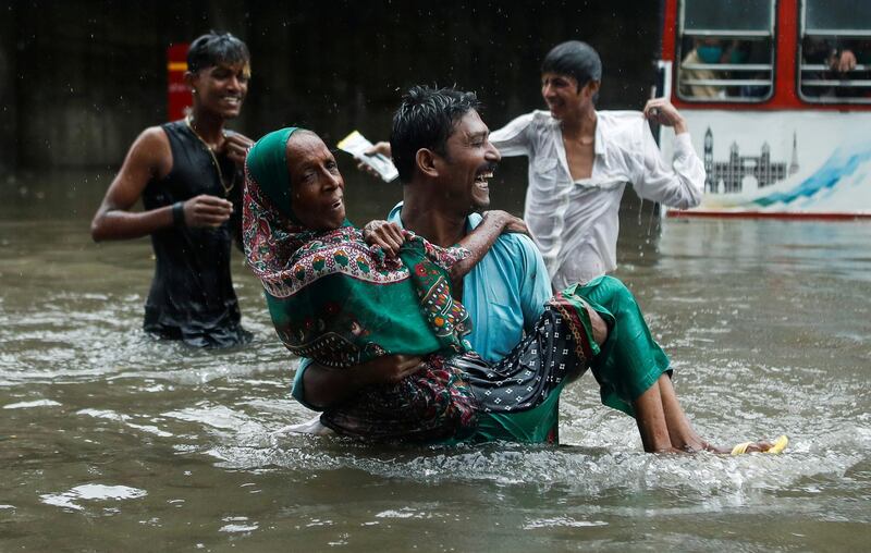 A man carries an elderly woman as they cross a waterlogged street during heavy rainfall in Mumbai, India. Reuters