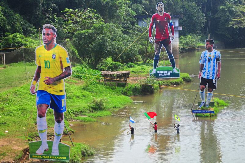 Fans wave flags next to the giant cutouts of Brazil's Neymar, Portugal's Cristiano Ronaldo and Argentina's Lionel Messi in India's Kerala state. AFP