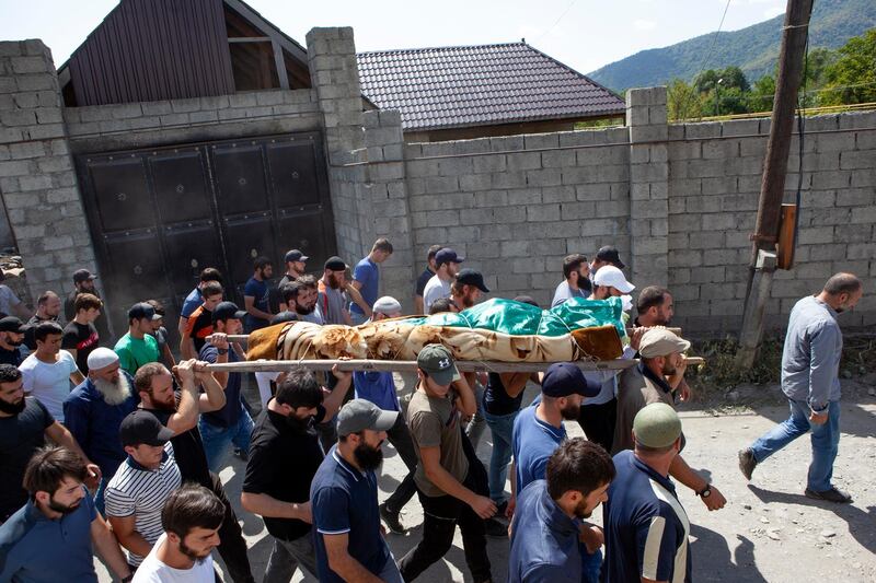 FILE-In this Aug. 29, 2019 file photo people carry the body of the victim who has been identified as Zelimkhan Khangoshvili, a Georgian Muslim during the funeral in Duisi village, the Pankisi Gorge valley, in Georgia. Germanyâ€™s foreign ministry says it has expelled two Russian diplomats after prosecutors announced they suspected Moscowâ€™s involvement in the brazen daylight slaying of a Georgian man in Berlin. (AP Photo/Zurab Tsertsvadze)