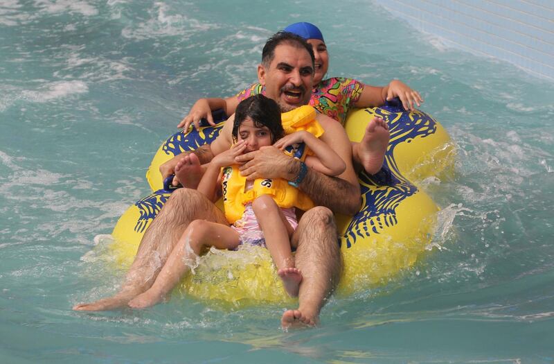 A man shares a water to with children at an indoor water park.