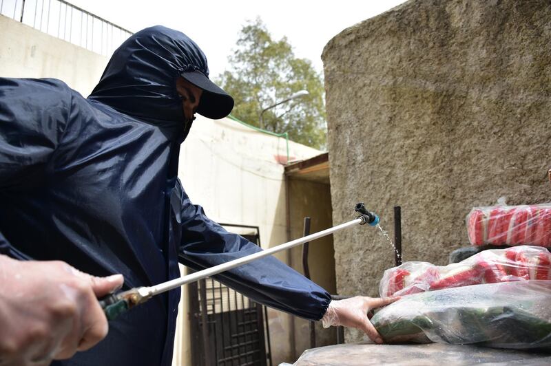 A member of an NGO in a protective suit disinfects bags containing foods in Damascus, Syria, on 6, April 2020. EPA