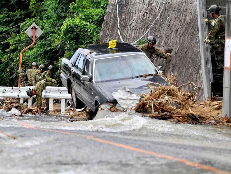 Japan Ground Self-Defense Force members search missing people near a damaged taxi after flooding caused by heavy rains hit Hiroshima, southwestern Japan, Thursday, on July 12, 2018. Kyodo News via AP