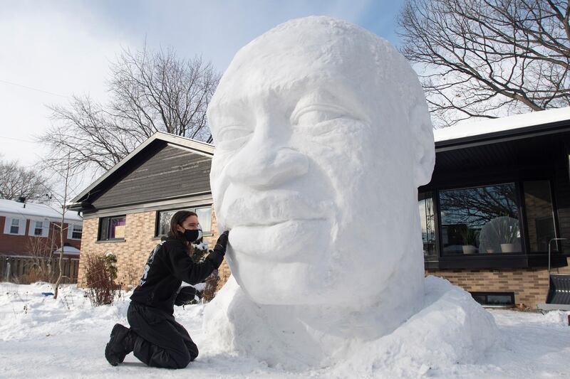 Timothee de Sandro puts the finishing touches on a snow sculpture of George Floyd in front of his house, Wednesday, Dec. 23, 2020 in Quebec City. De Sandro was shaken by the May, 2020 death of Floyd and wanted to pay tribute to him.  (Jacques Boissinot/The Canadian Press via AP)